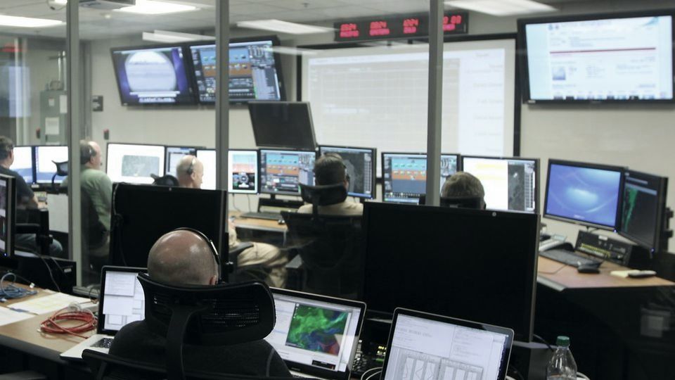 An office with rows of desks and banks of monitors