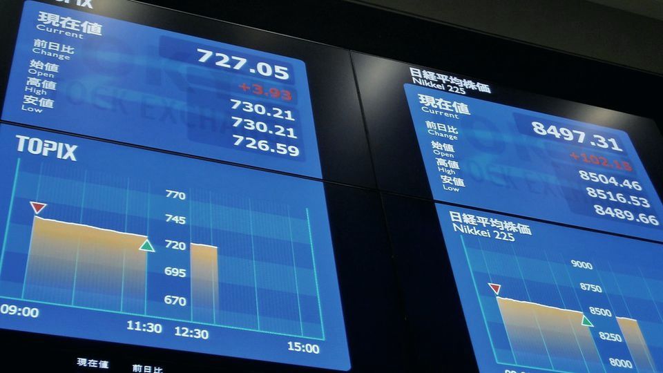 Screens showing stock prices and an index chart at an exchange