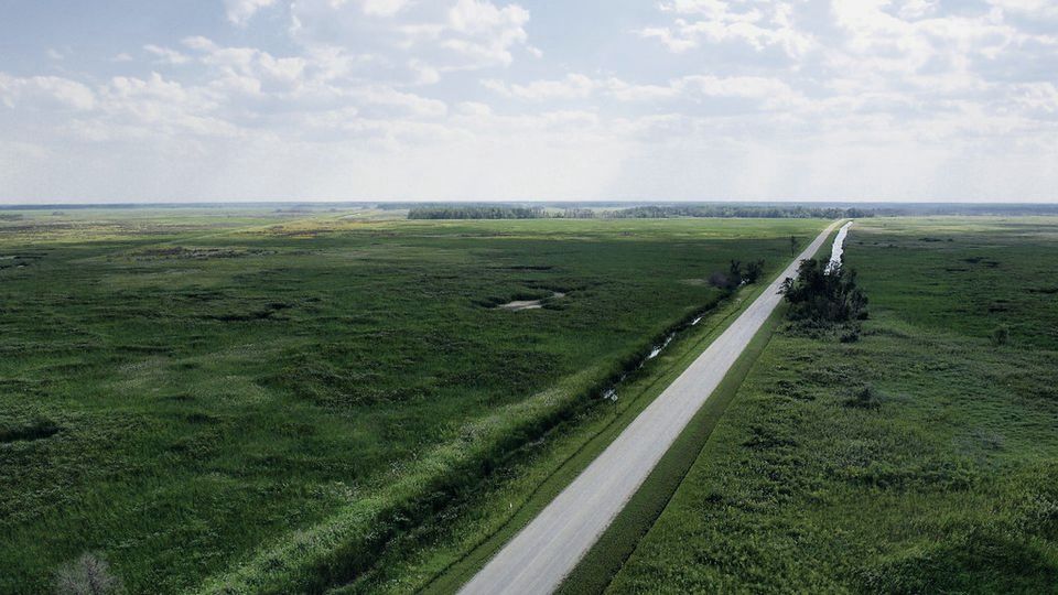 A straight road running through green fields toward the horizon