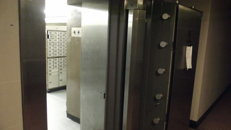 An open bank vault door leading to safe-deposit boxes